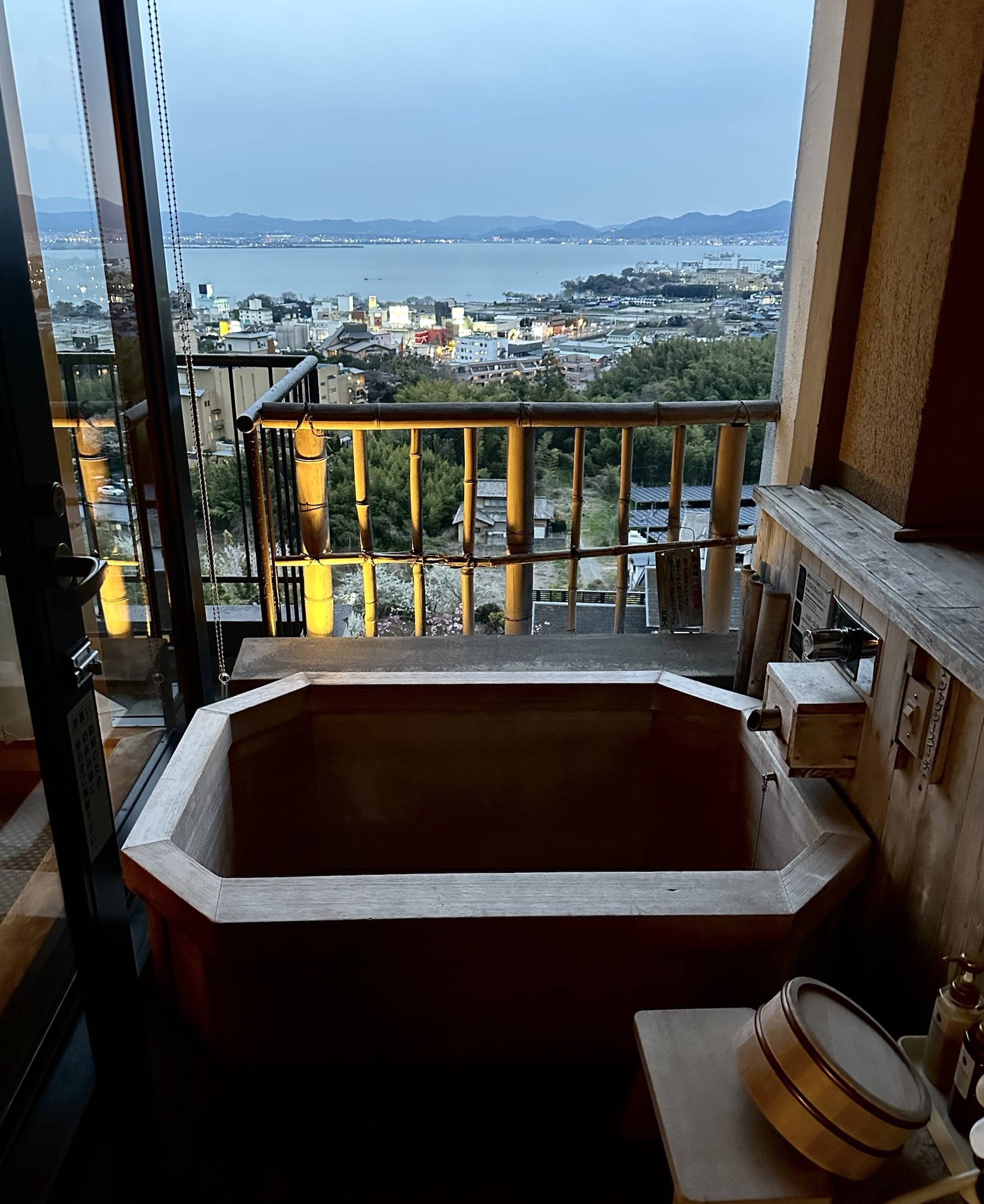 An outdoor private onsen in Yuzanso, a ryokan in Ogoto Onsen (Otsu). The private cypress bath overlooks Lake Biwa at dusk. 