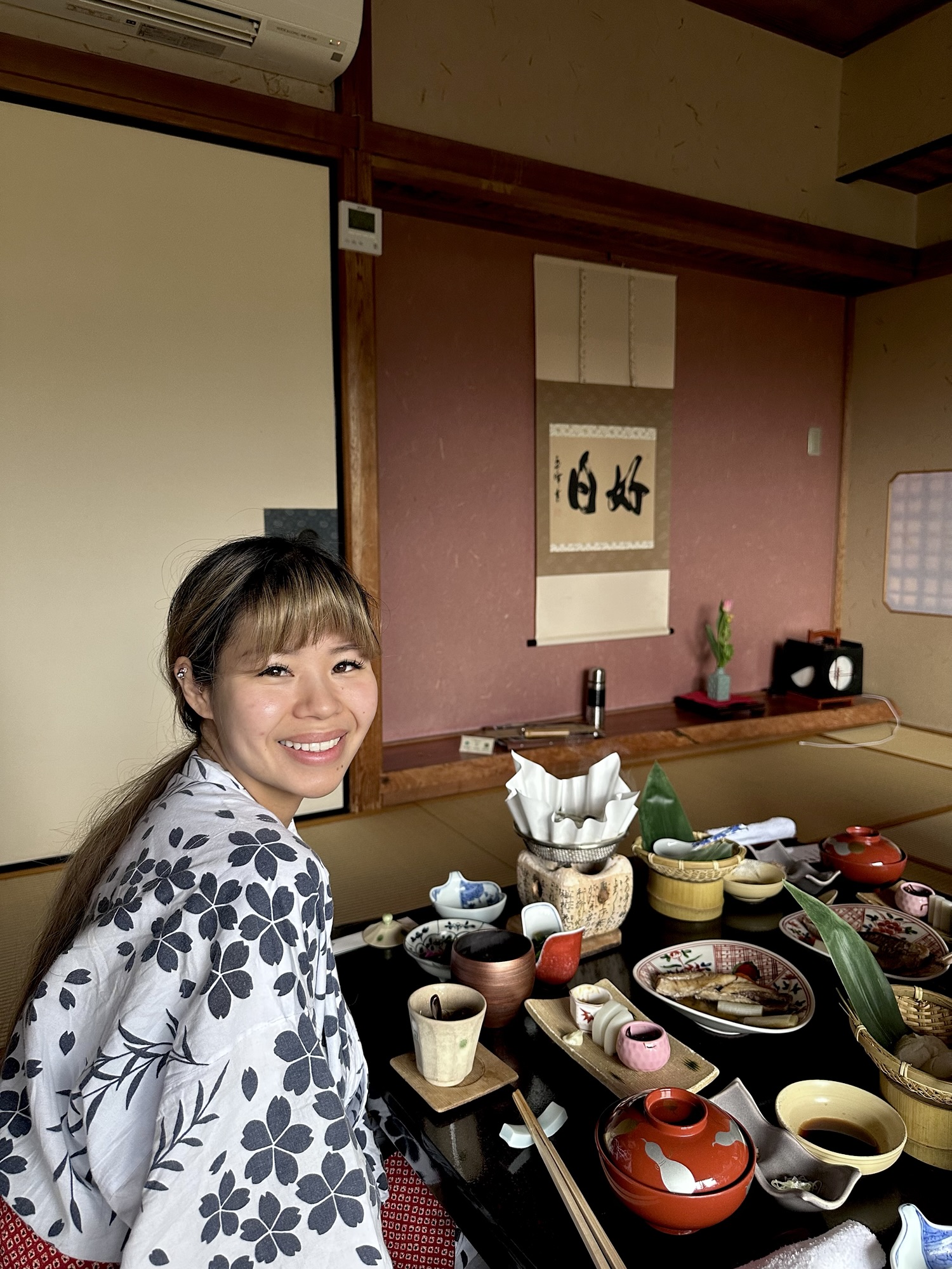 Audrey in a ryokan wearing a blue and white yukata and sitting next to a traditional Japanese breakfast set up.
