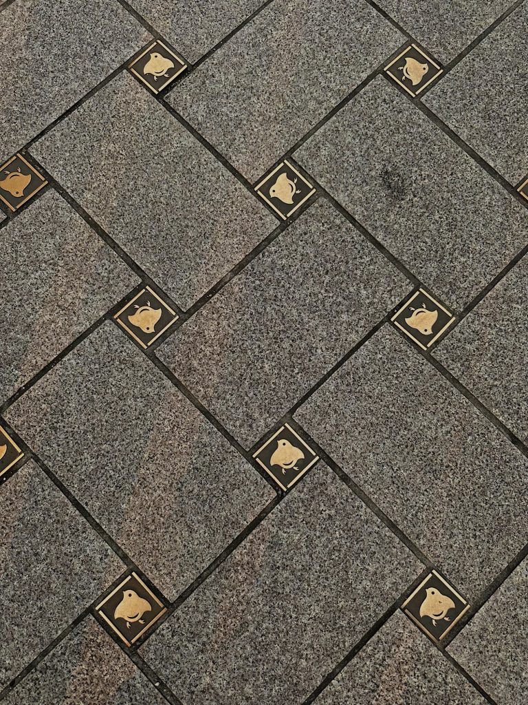 Close up of stone pavement in Pontocho Alley with small gold plover bird symbols set between the tiles