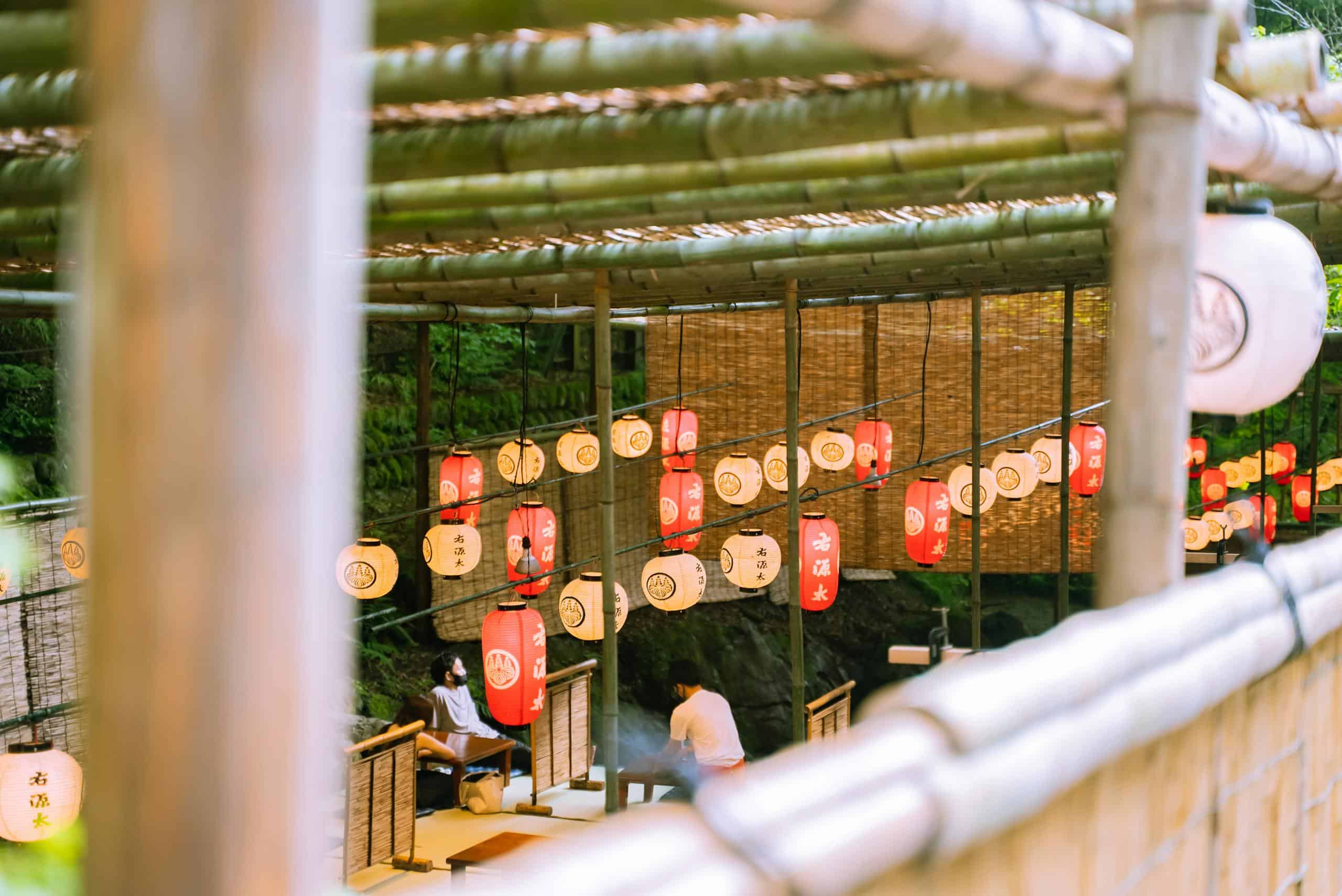 Outdoor seating area in a Japanese restaurant decorated with red lanterns and bamboo elements.