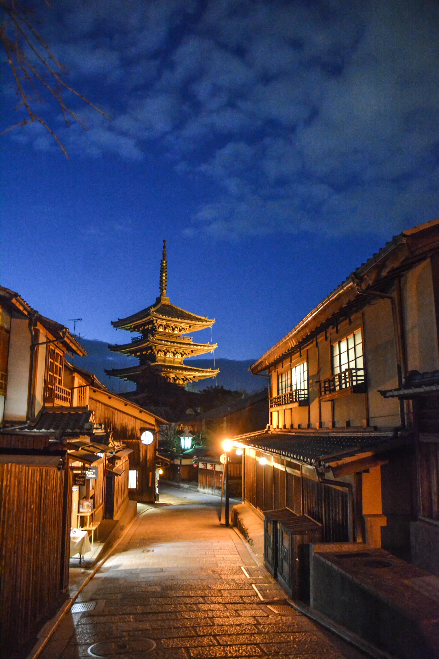 Twilight scene of the Yasaka Pagoda in Kyoto's historic district with traditional wooden architecture.