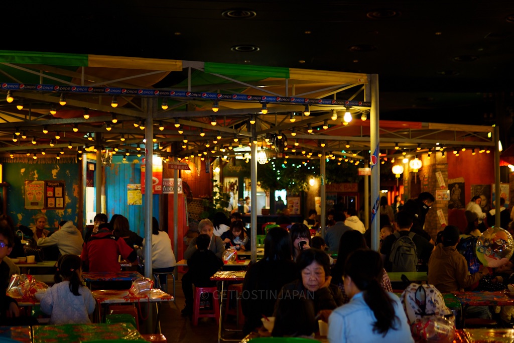 Noodles Bazaar dining area inside the Cup Noodles Museum with colorful food stalls and visitors eating during a day trip to Yokohama.