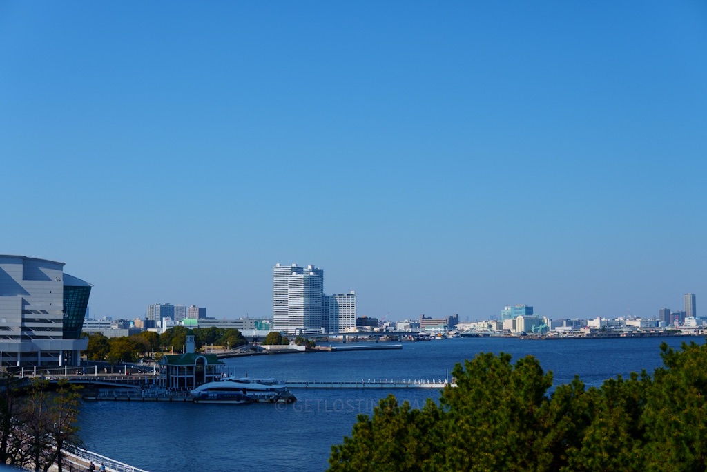 Sunny waterfront view of Yokohama Bay with blue water, city buildings, and a clear sky.