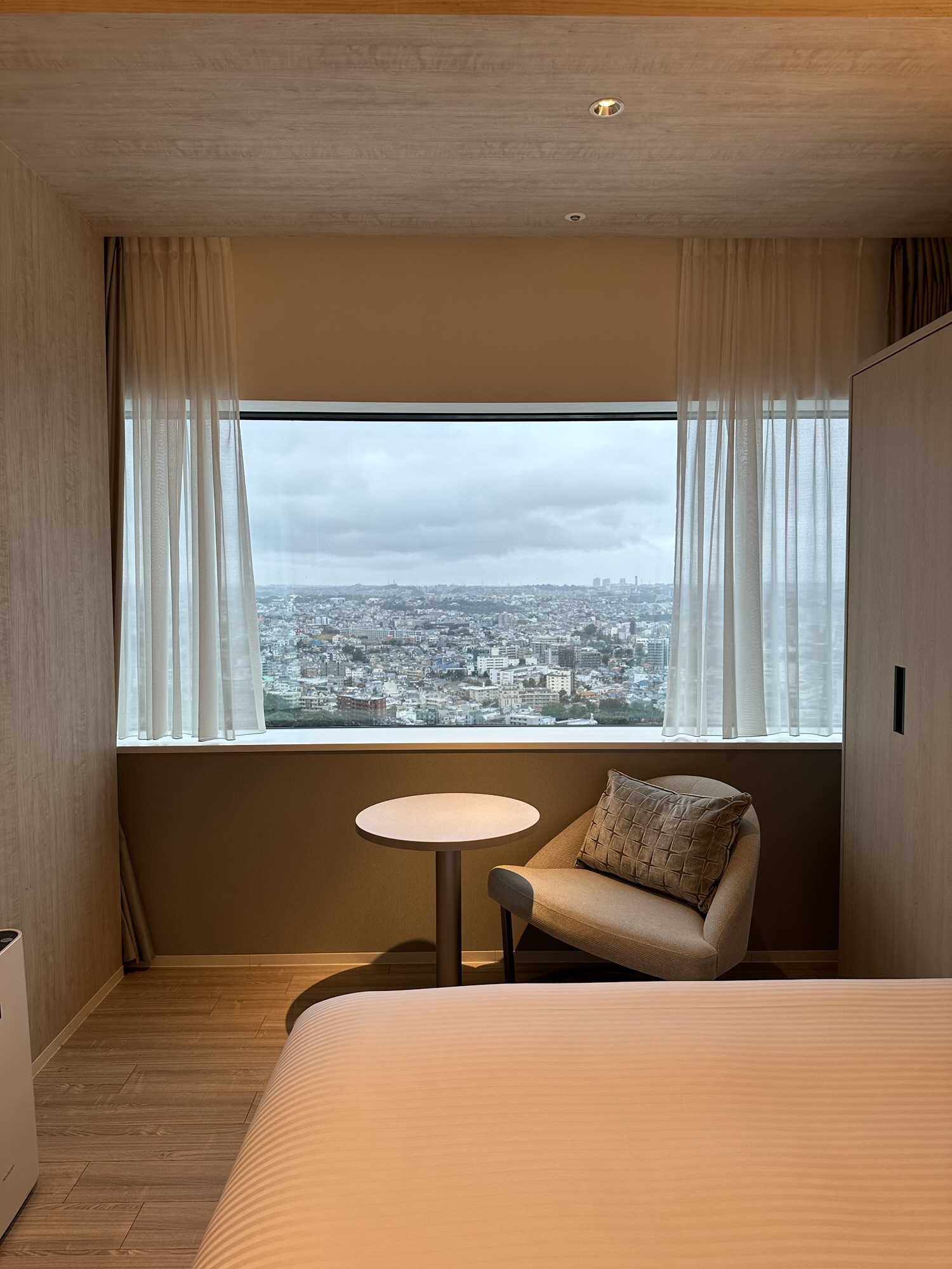 Modern hotel room at Mitsui Garden Yokohama Minatomirai Premier with a large window overlooking the city skyline.