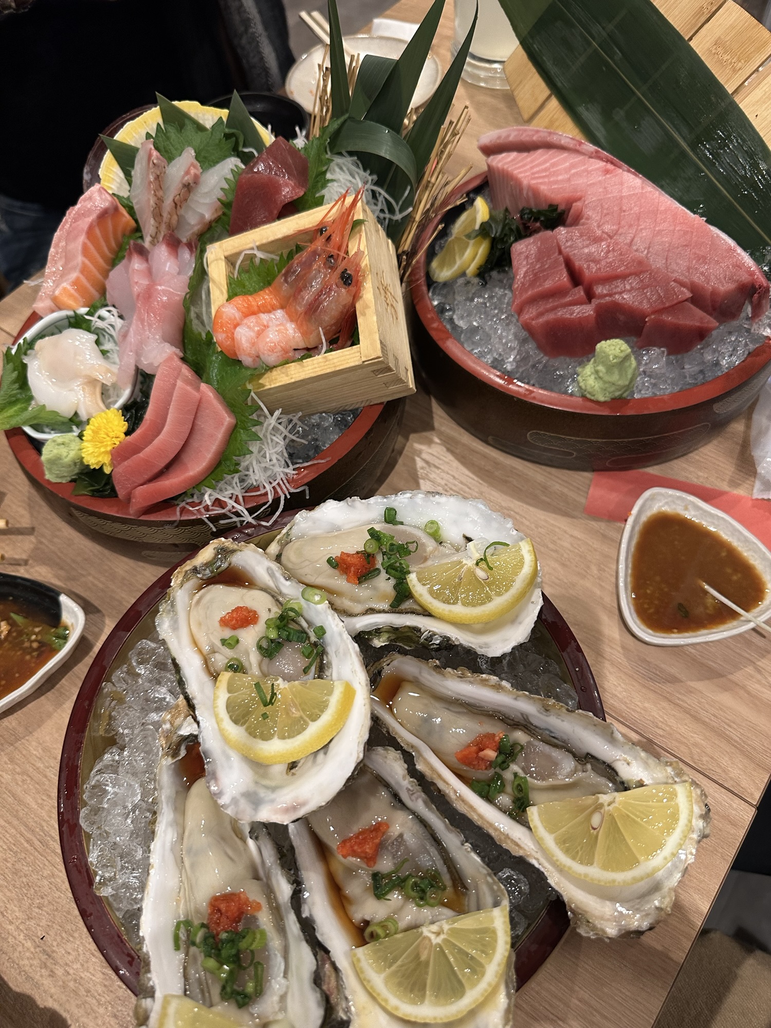 Fresh sashimi, tuna, shrimp, scallops, and oysters served on ice at a seafood izakaya in Yokohama.